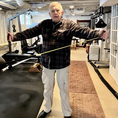 Older fit man doing upper back exercise with bands.