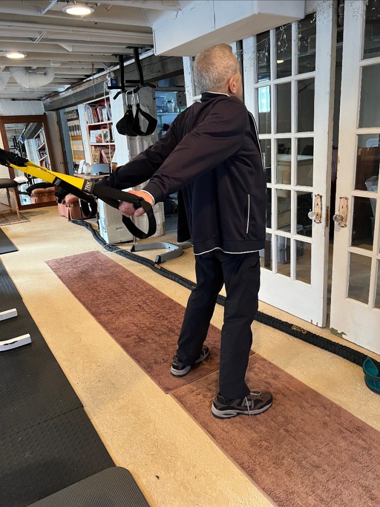 Older man stretching the front of his shoulders.