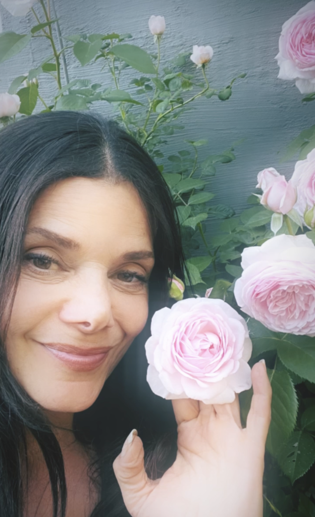 Woman standing near beautiful, pink, fragrant roses.