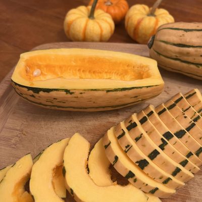 Delicata squash cut in half and sliced thin to prepare for roasting.