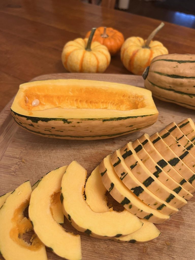 Delicata squash cut in half and sliced thin to prepare for roasting.