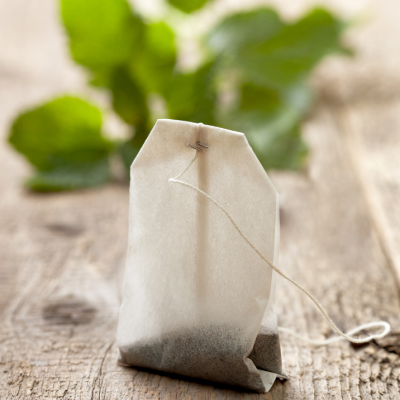 Tea bag sitting on a table with leaves around it.