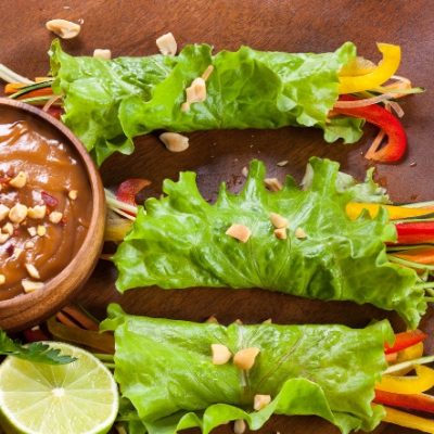 Chicken wrapped in lettuce with veggies and a side of peanut sauce.