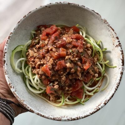 Spaghetti sauce over zucchini noodles in a pretty white bowl.