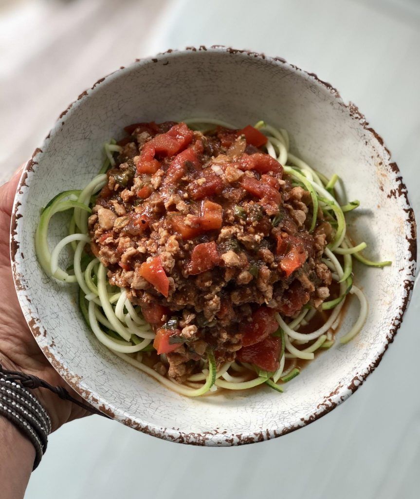 Spaghetti sauce zucchini noodles in a pretty white bowl.