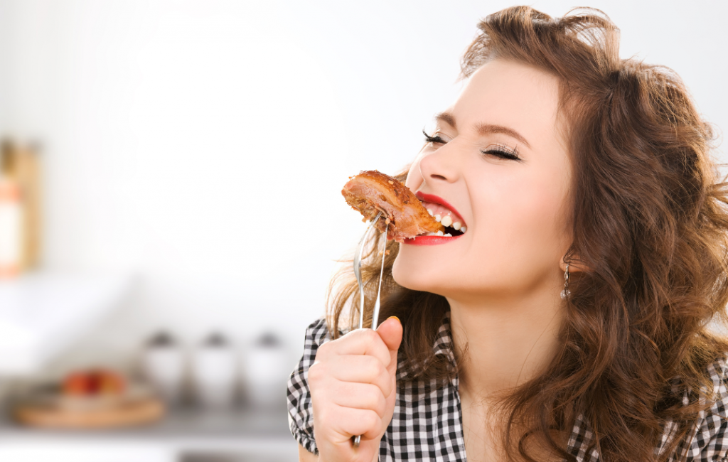 Pretty woman eating meat on a fork.