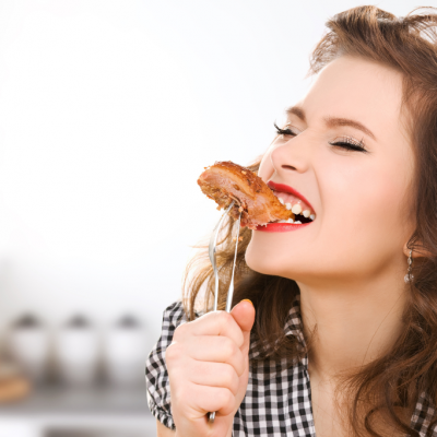 Pretty woman eating meat on a fork.