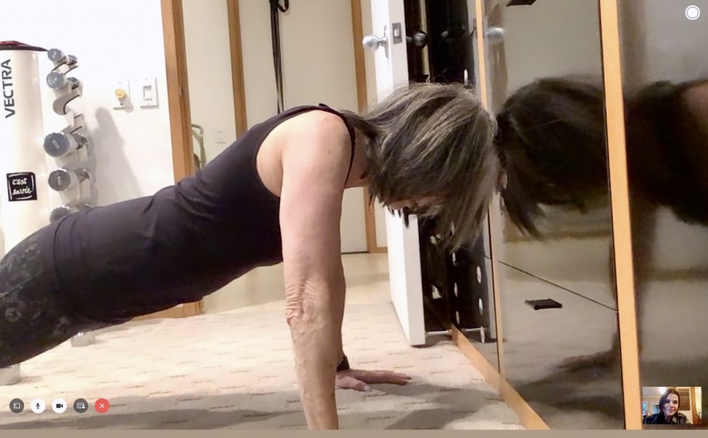 Fit older woman performinga hand plank on the floor.