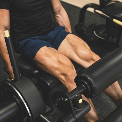 Man performing a leg extension exercise on a machine. Show his defined quadricep muscles.