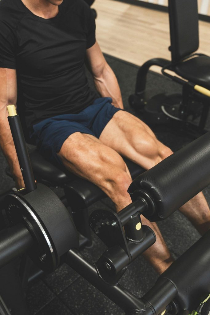 Man performing a leg extension exercise on a machine. Show his defined quadricep muscles.