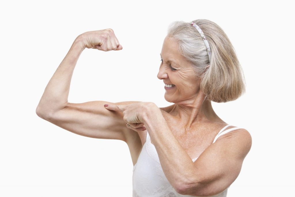 In shape older woman flexing her bicep muscle.
