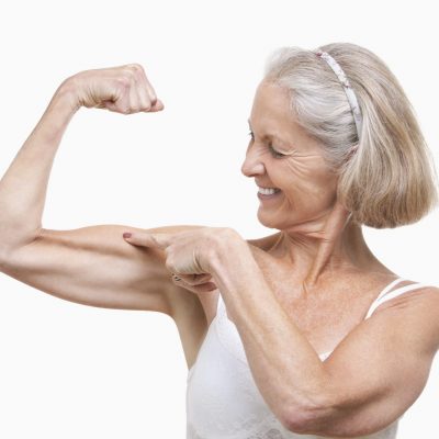 In shape older woman flexing her bicep muscle.