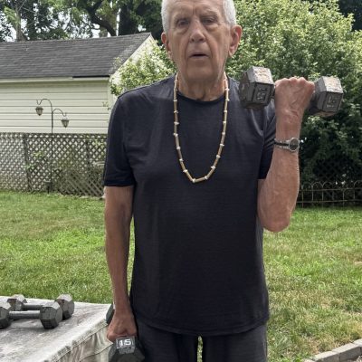 Older man lifting weights outside.