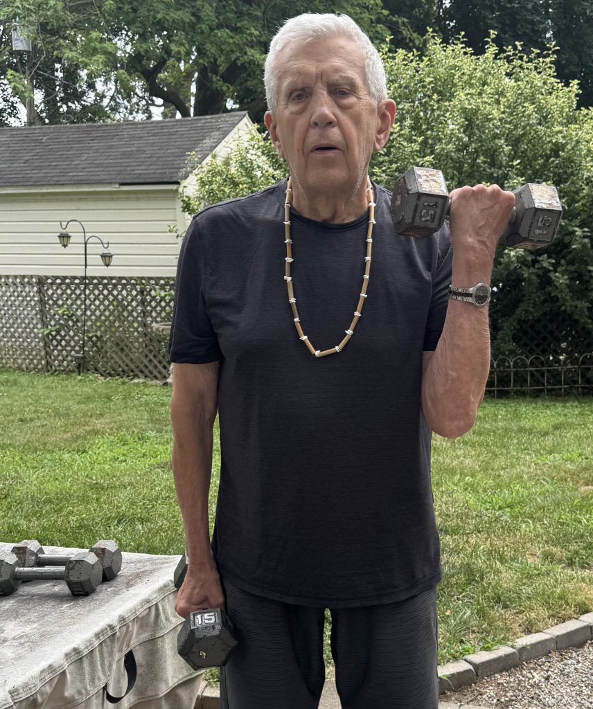 Older man lifting weights outside.