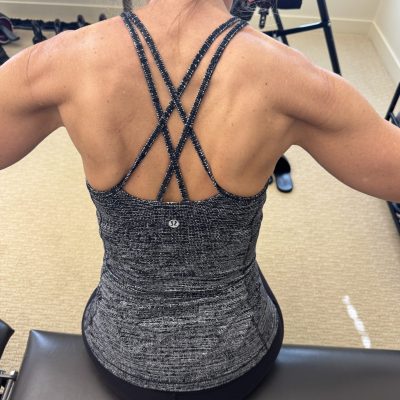 Very fit woman back in a workout top, showing muscle definition.