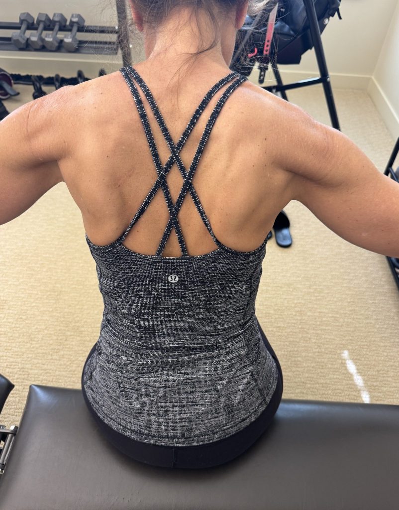 Very fit woman back in a workout top, showing muscle definition.