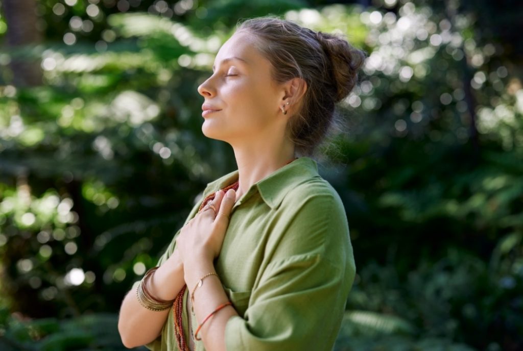 Woman crossing her arms across her chest smiling, happy and peaceful.