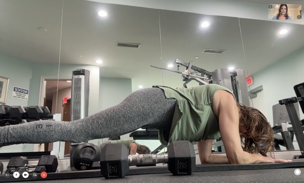 Woman doing a plank in a gym with a virtual personal trainer.