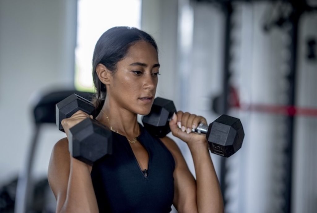Young woman working out with dumbbells.